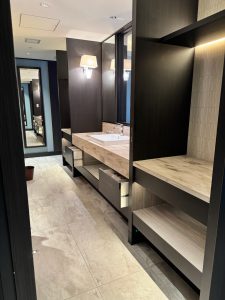 Bathroom sink area with shelves for luggage and large mirrors at Hotel Allamanda Aoyama