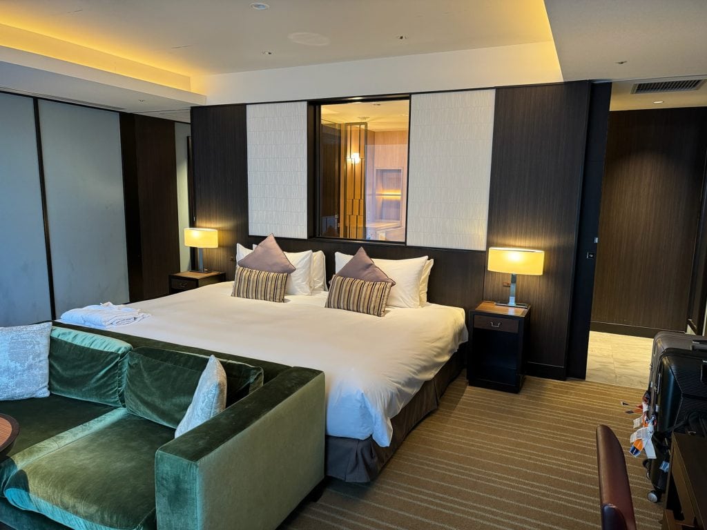 Spacious king bed with green velvet sofa and ambient lighting at Hotel Allamanda Aoyama Tokyo.