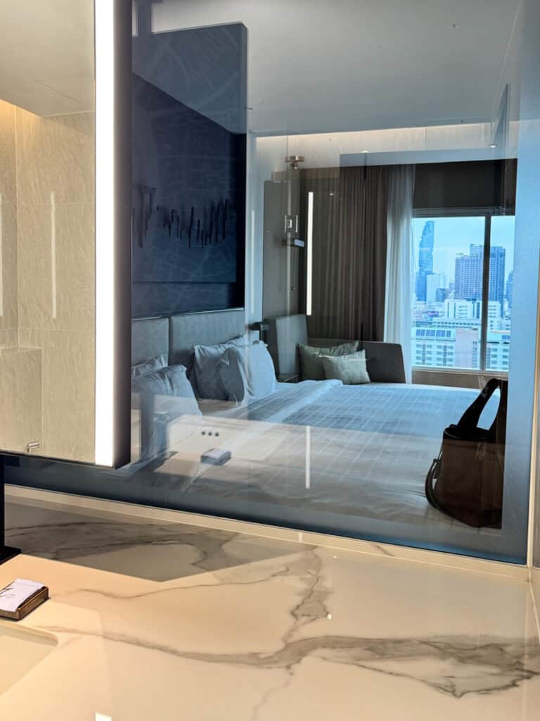 View of the Pathumwan Princess Hotel bed and Bangkok skyline viewed through the bathroom window