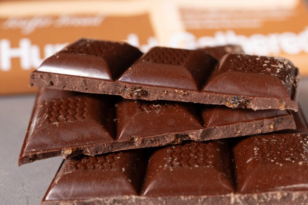 Close-up of Hunted + Gathered Milk Chocolate + Hot Cross Bun bar, showing glossy surface with visible raisins and inclusions.