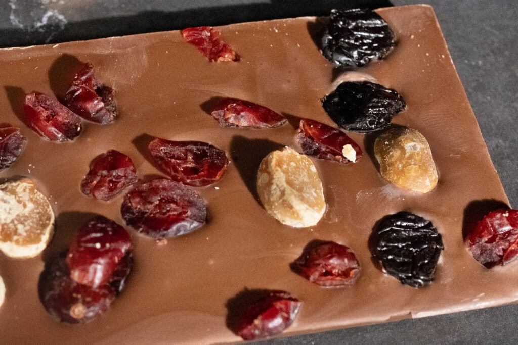 Close-up of Koko Black Cranberry, Macadamia & Cherry chocolate with visible fruit and nut inclusions.