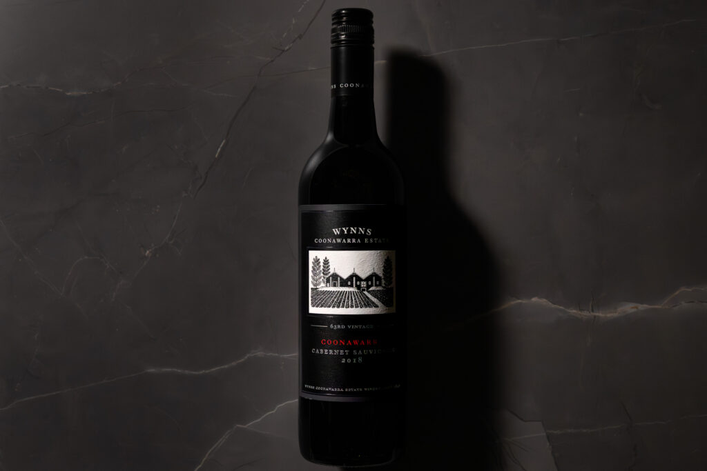 Bottle of Wynns Coonawarra Estate Cabernet Sauvignon 2018 on dark marble background, shot in moody light