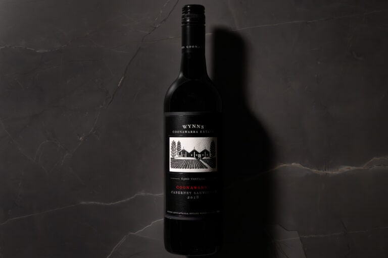 Bottle of Wynns Coonawarra Estate Cabernet Sauvignon 2018 on dark marble background, shot in moody light