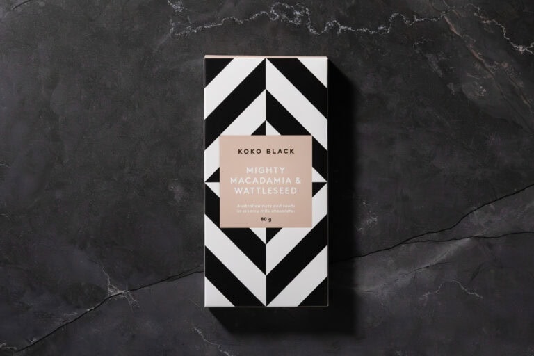 Mighty Macadamia and Wattleseed chocolate bar packaging photographed flat on dark background