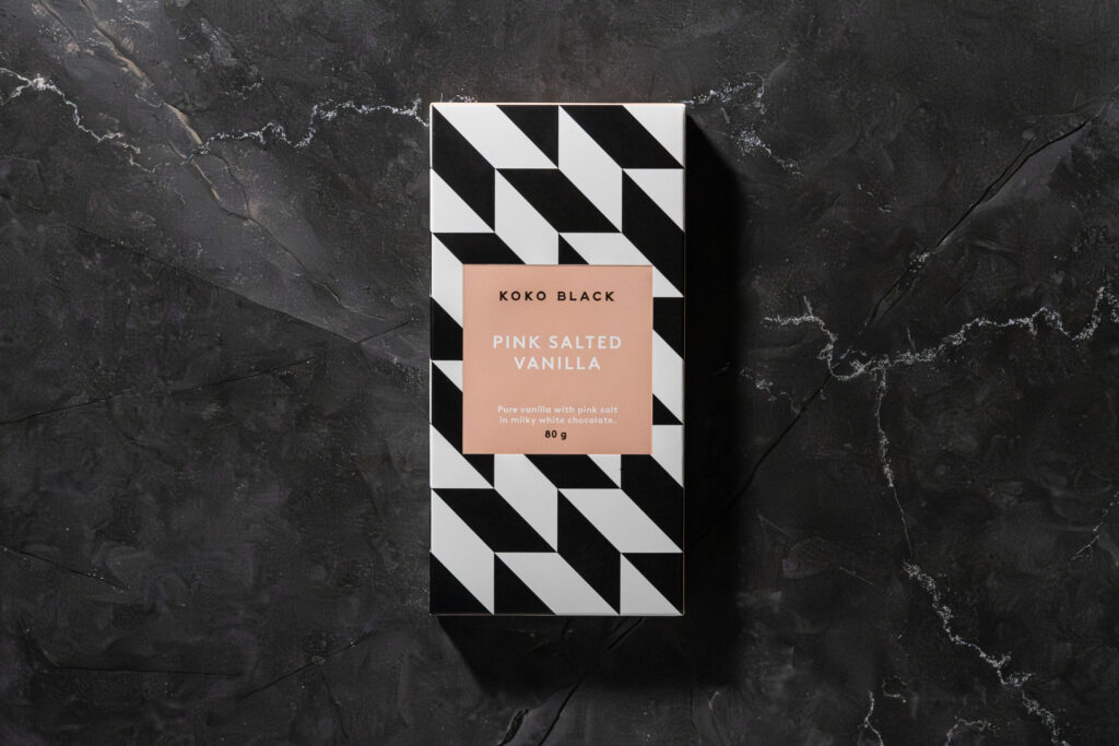 Koko Black Pink Salted Vanilla chocolate bar in its packaging on dark stone