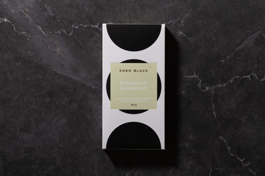 Koko Black Pistachio Ganachio chocolate bar in its packaging on dark stone