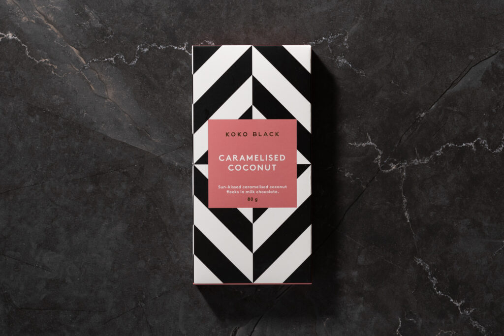 Koko Black Caramelised Coconut chocolate bar in its black and coral striped packaging