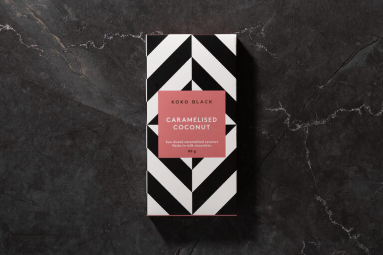 Koko Black Caramelised Coconut chocolate bar in its black and coral striped packaging