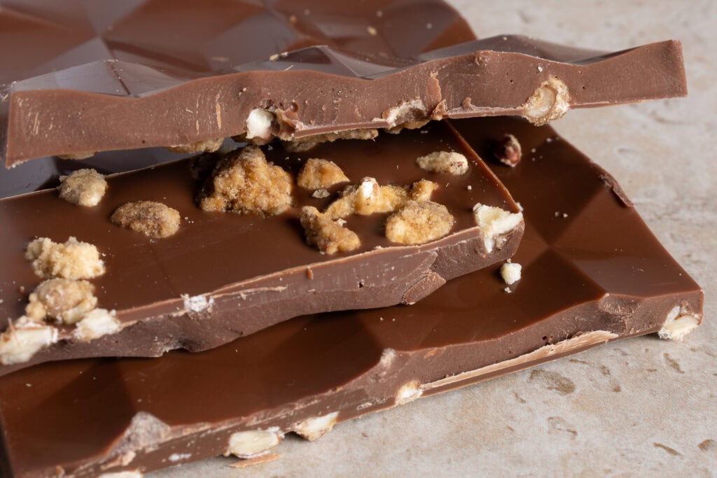 Broken pieces of Zokoko Coffee Pecan milk chocolate showing pecan texture