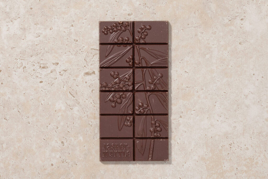 Jasper + Myrtle Blueberry Dark Chocolate bar with embossed botanical design on stone surface