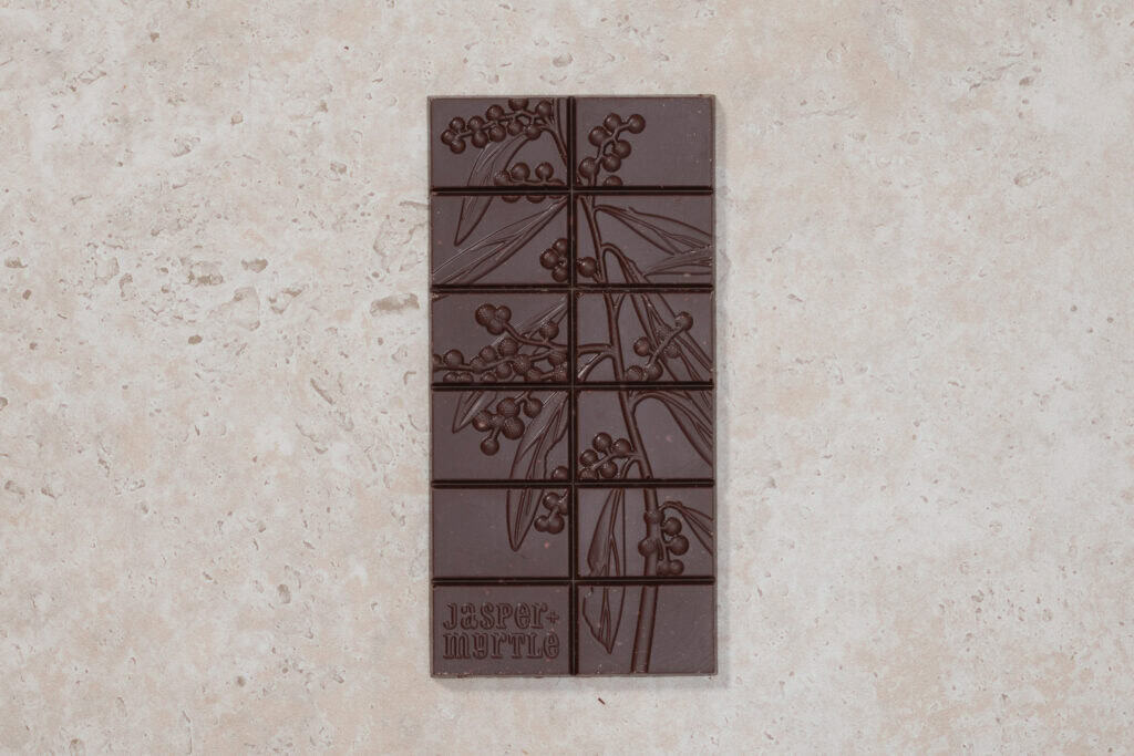 Jasper + Myrtle Ginger & Coconut 65% dark chocolate bar with embossed botanical design on a stone surface.