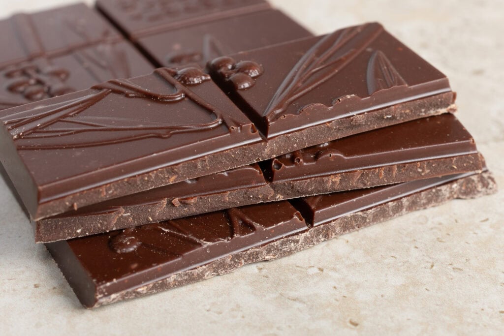 Stacked pieces of Jasper + Myrtle Ginger & Coconut 65% dark chocolate showing the interior texture and coconut flecks.