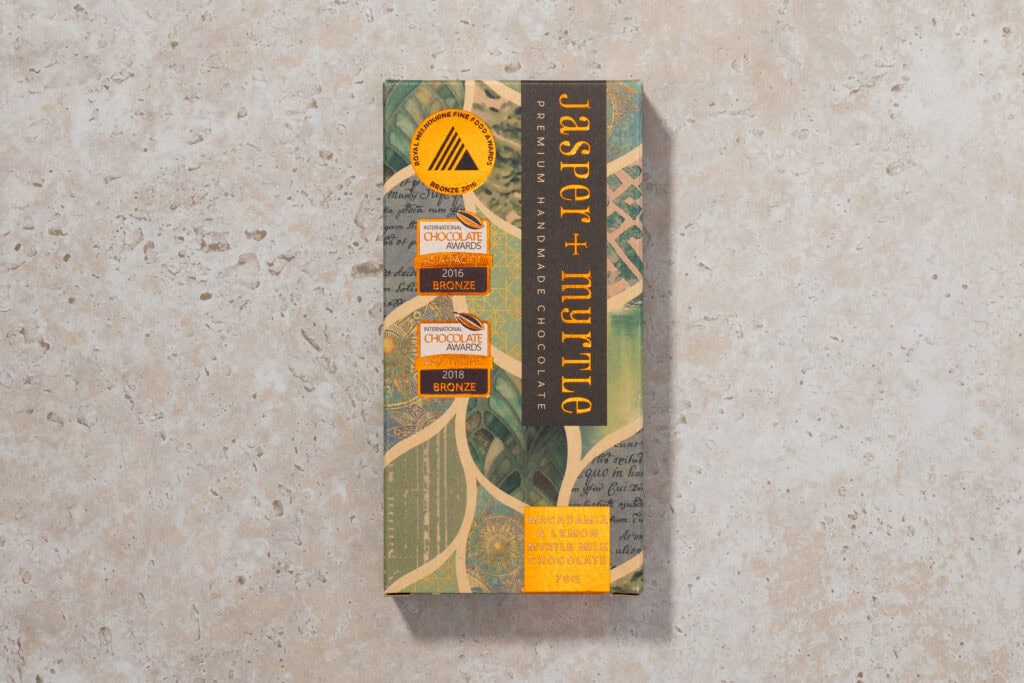 Jasper + Myrtle Macadamia & Lemon Myrtle 45% milk chocolate bar in packaging on stone surface