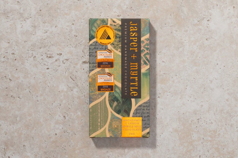 Jasper + Myrtle Macadamia & Lemon Myrtle 45% milk chocolate bar in packaging on stone surface