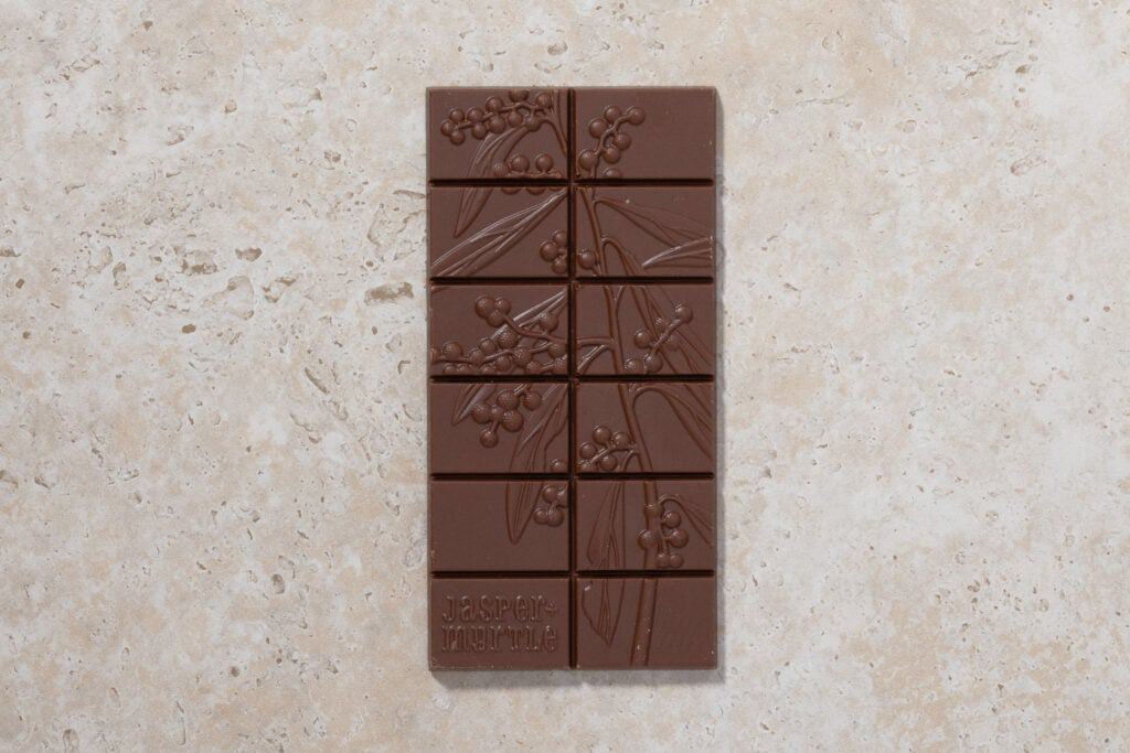 Jasper + Myrtle 45% milk chocolate bar with embossed lemon myrtle design on stone surface