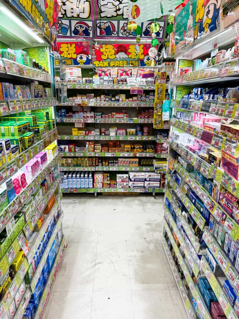 Narrow pharmacy aisle inside a Donki store in Tokyo filled with stacked shelves and bright lighting