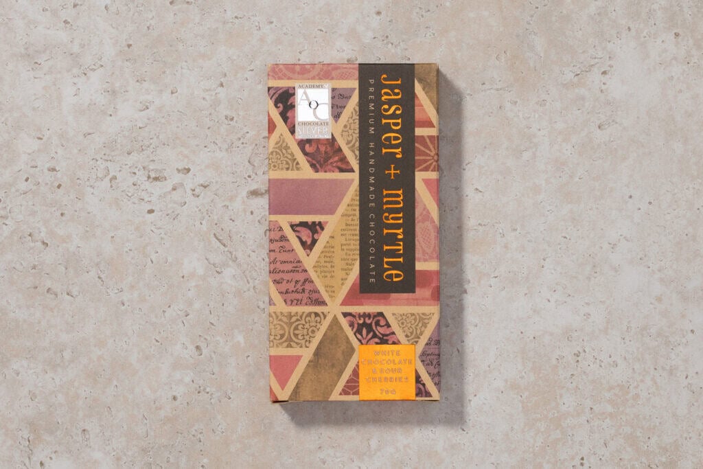 Jasper + Myrtle White Chocolate & Sour Cherries bar in original packaging on a light stone surface.