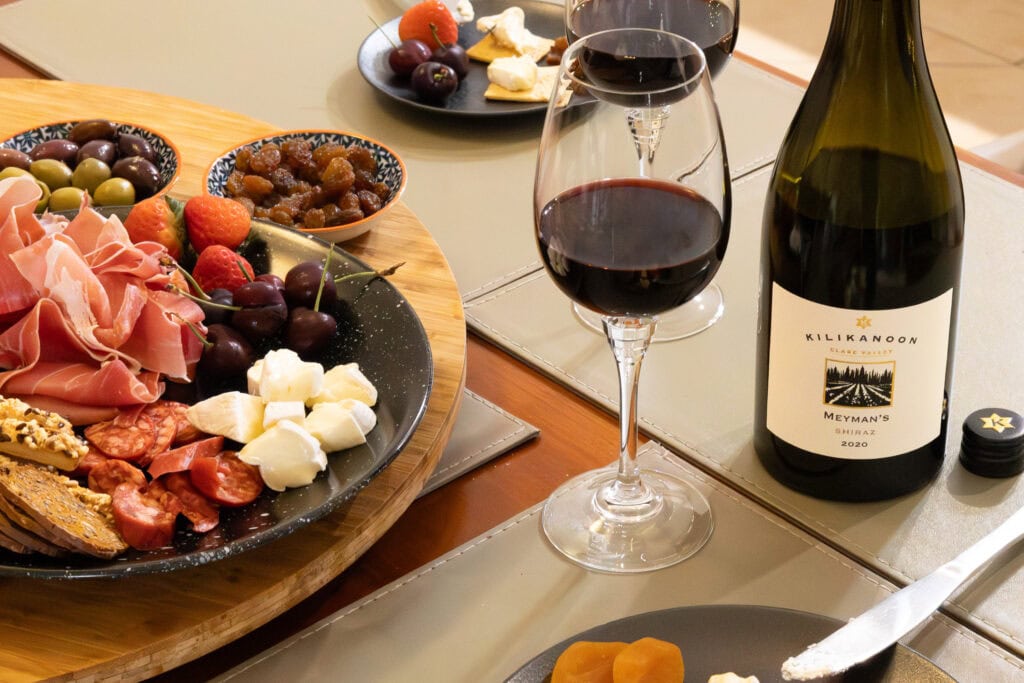 Kilikanoon Meyman’s Shiraz 2020 served beside a grazing board with cured meats, olives, strawberries, and cheeses