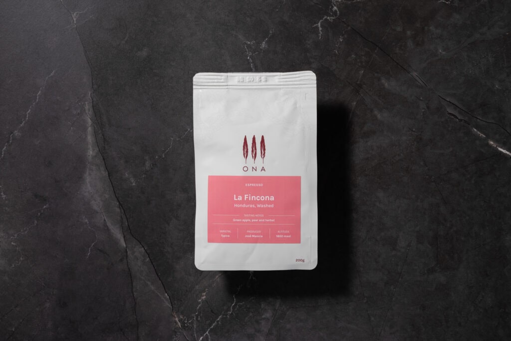 ONA La Fincona espresso coffee beans from Honduras on a dark stone surface