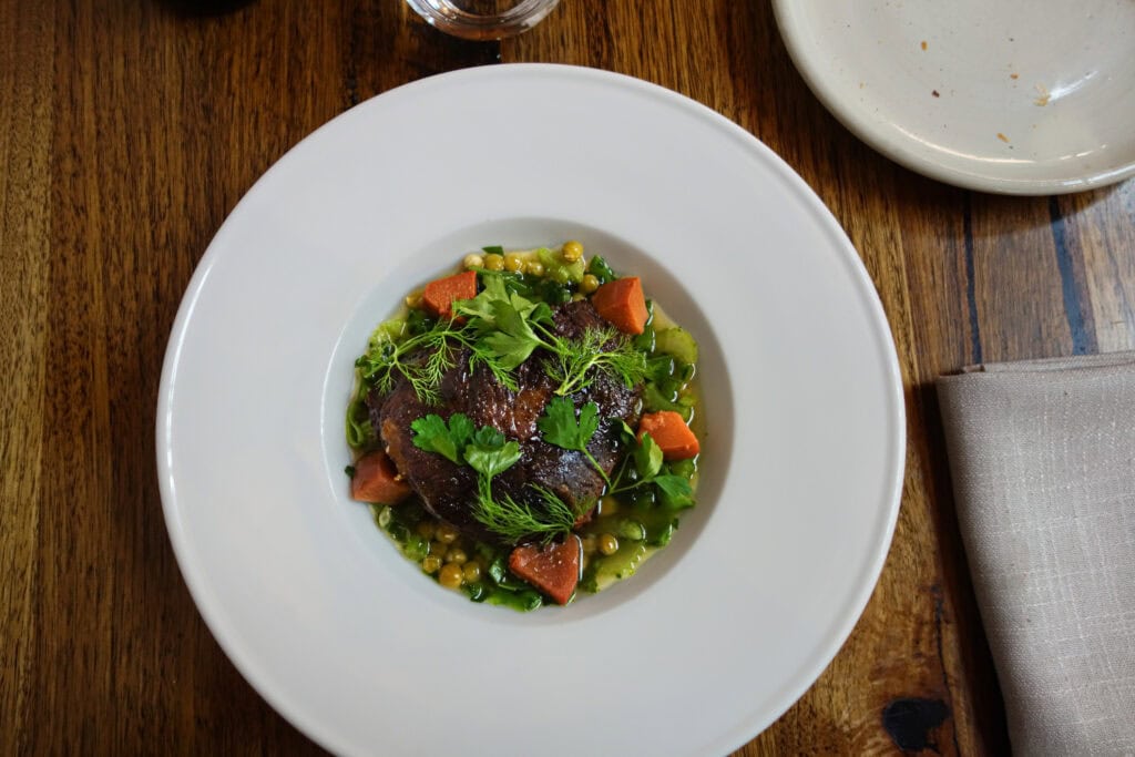 Beef cheek confit with jade peas, quince and chicken broth served at Topiary Restaurant in Adelaide, South Australia.