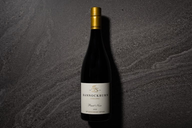 A bottle of Bannockburn Geelong Pinot Noir 2024 standing on a dark grey stone surface, with its cream 50th Anniversary Vintage label and gold capsule visible.