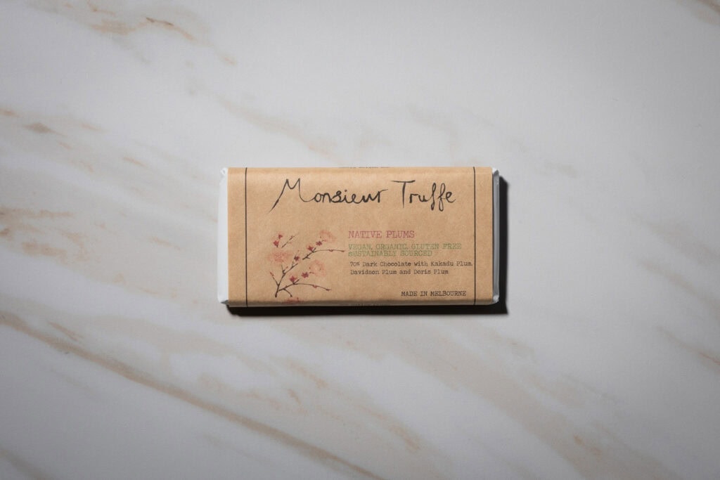 Monsieur Truffe Native Plums 70% dark chocolate bar in its packaging on a marble surface