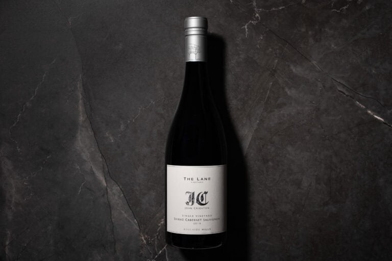 Bottle of The Lane John Crighton Single Vineyard Shiraz Cabernet 2010 on a dark stone background