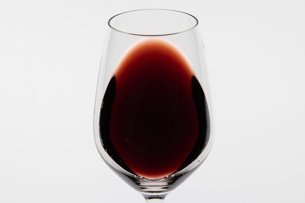 Glass of deep garnet red wine showing the colour of The Lane John Crighton 2010